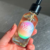 Hand holding a bottle labeled 'Double Take' with a colorful label.