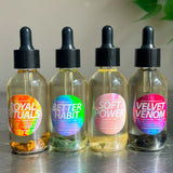 Four glass bottles with colorful labels on a reflective surface.
