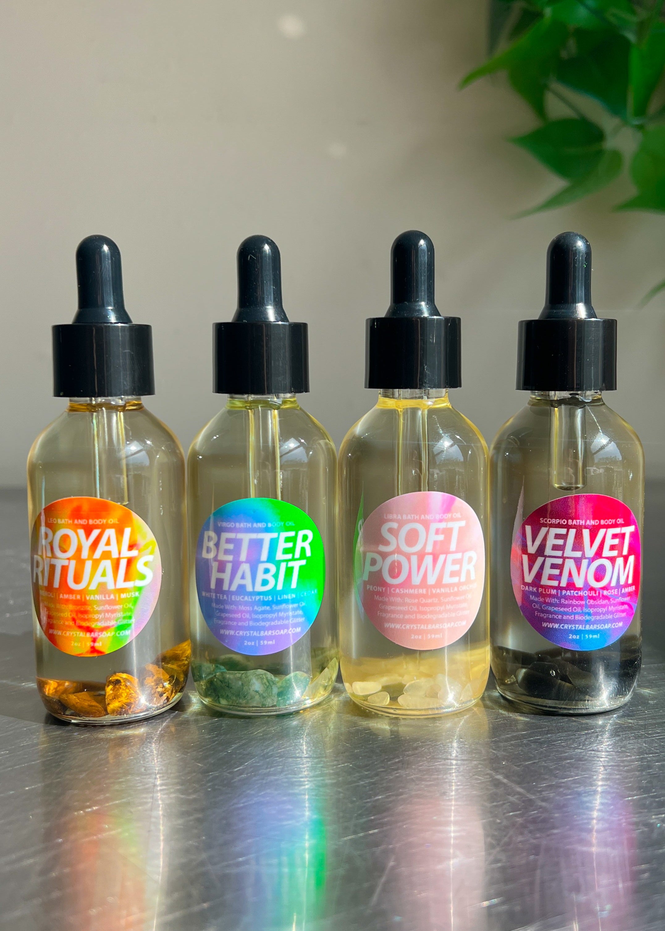 Four glass bottles with colorful labels on a reflective surface.