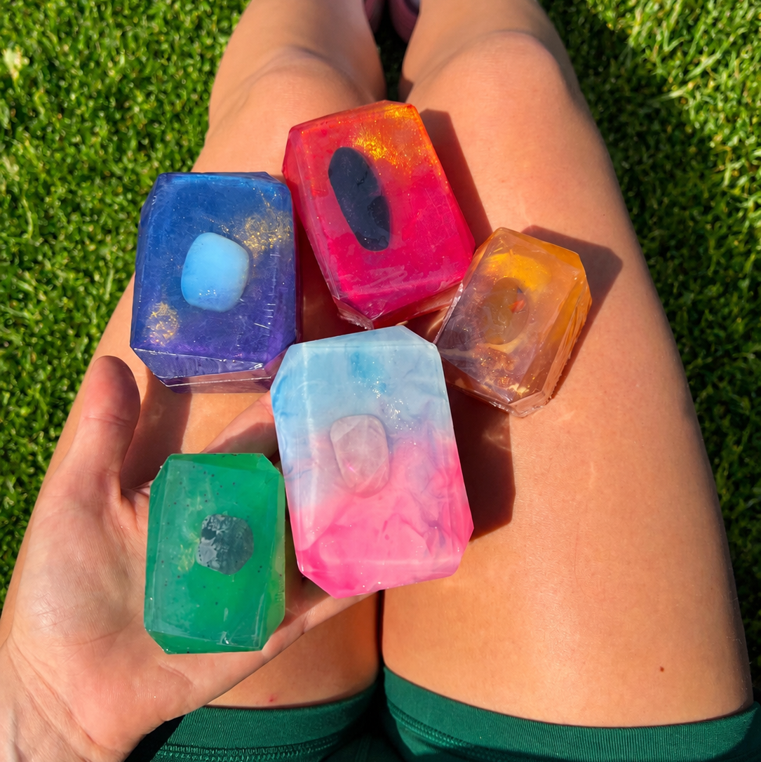 Colorful crystal soaps held by a person sitting on grass