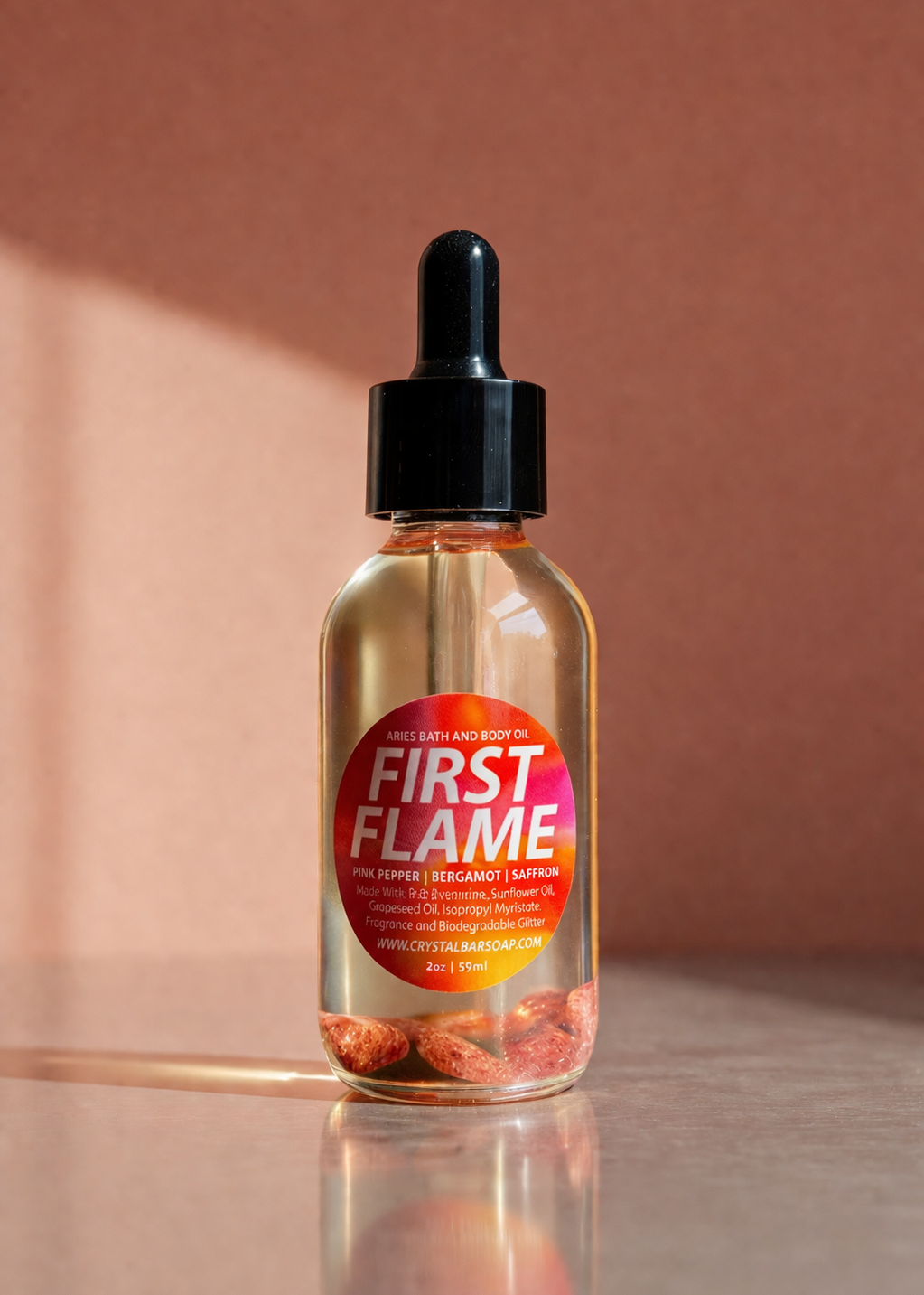 Bottle of 'First Flame' with a dropper on a reflective surface and brown background