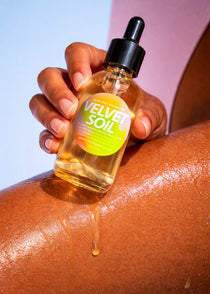 Hand applying a dropper of 'Velvet Soil' oil to skin